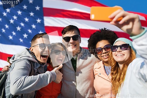 Image of smiling friends taking selfie with smartphone