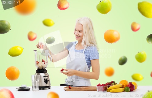 Image of smiling woman with blender preparing shake