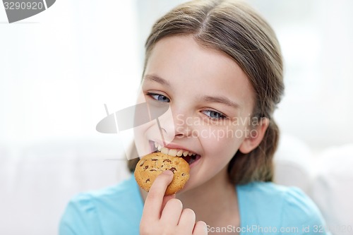 Image of smiling little girl eating cookie or biscuit