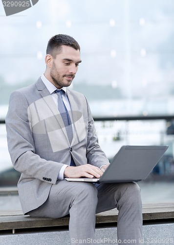 Image of businessman working with laptop outdoors