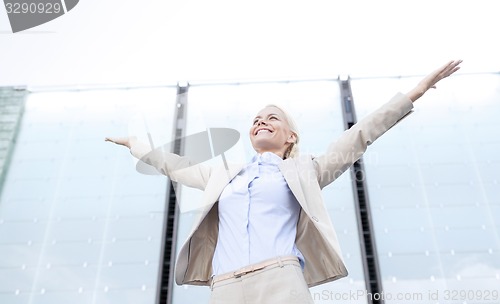 Image of young smiling businesswoman over office building