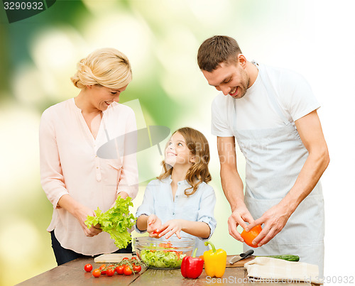 Image of happy family cooking vegetable salad for dinner