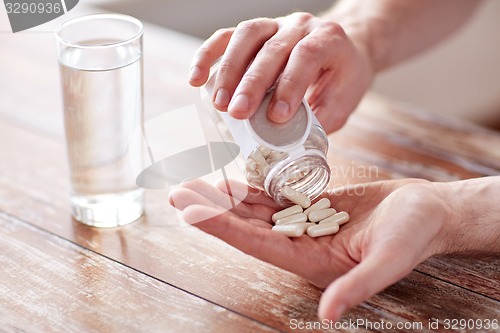 Image of close up of man pouring pills from jar to hand