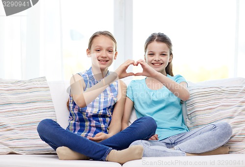 Image of happy little girls showing heart shape hand sign