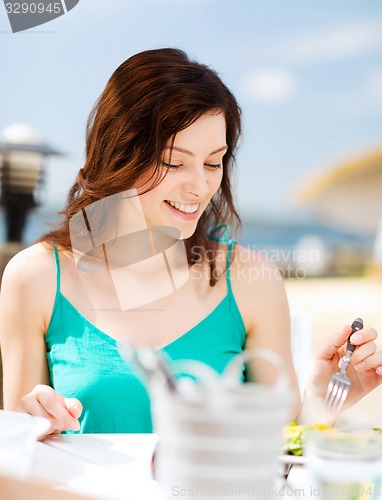 Image of girl eating in cafe on the beach