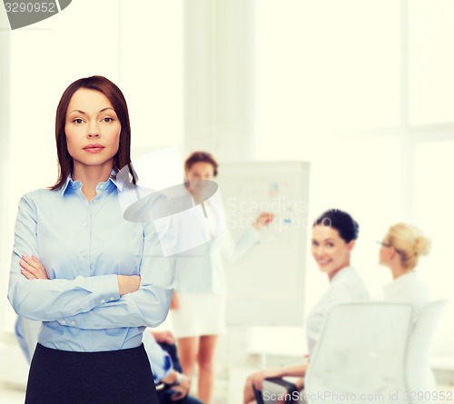 Image of smiling businesswoman with crossed arms at office