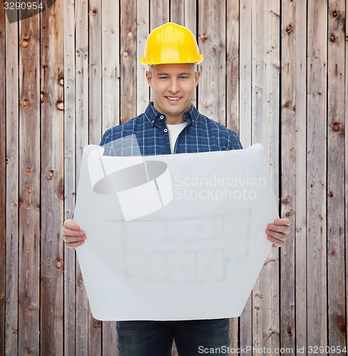 Image of smiling male builder in helmet reading blueprint