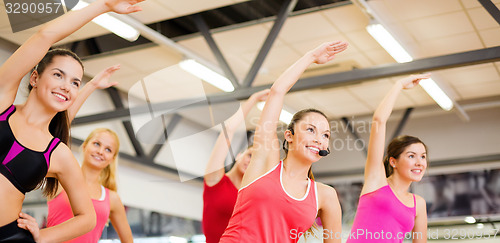 Image of group of smiling people stretching in the gym