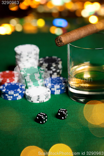 Image of close up of chips, dice, whisky and cigar on table