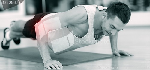 Image of smiling man doing push-ups in gym