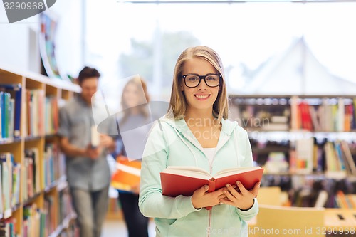 Image of happy student girl or woman with book in library