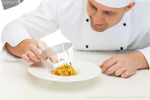 Image of happy male chef cook decorating dish