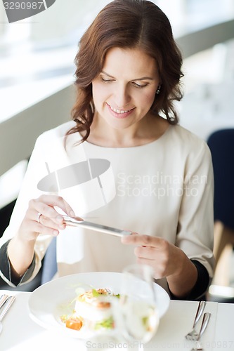 Image of happy woman with smartphone taking picture of food