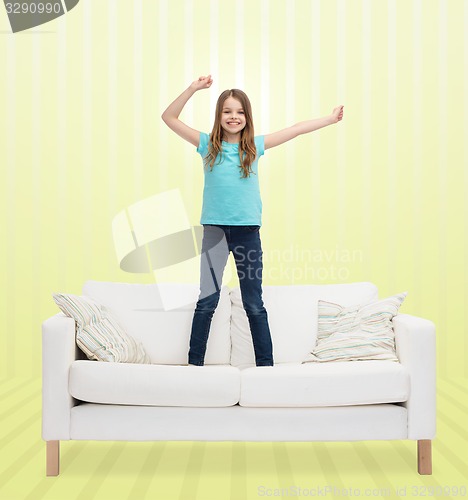 Image of smiling little girl jumping on sofa