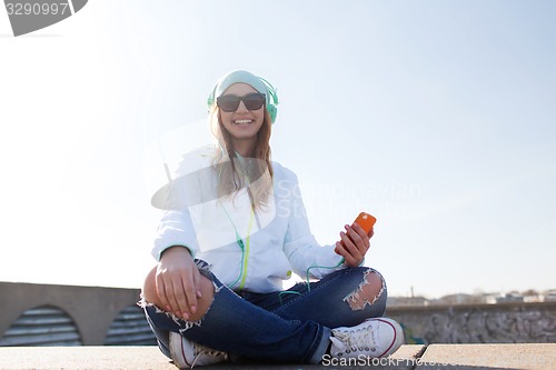 Image of happy young woman with smartphone and headphones