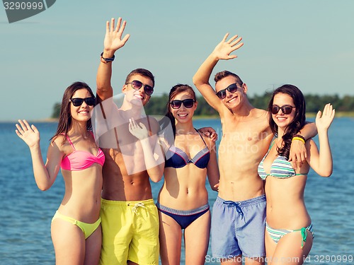 Image of smiling friends in sunglasses on summer beach