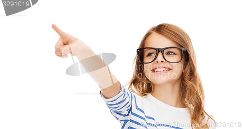 Image of cute little girl in eyeglasses pointing in the air