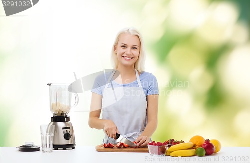 Image of smiling woman with blender preparing shake