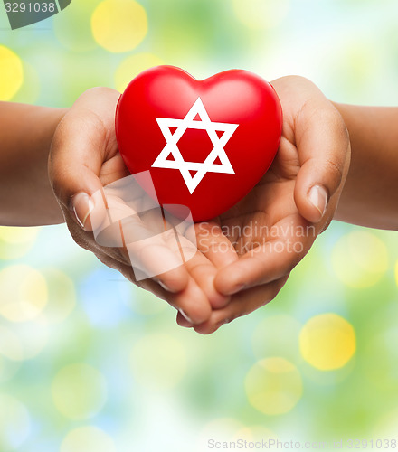 Image of close up of hands holding heart with jewish star