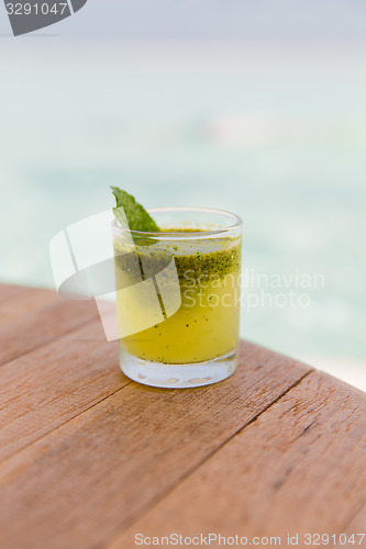 Image of glass of fresh juice or cocktail on table at beach