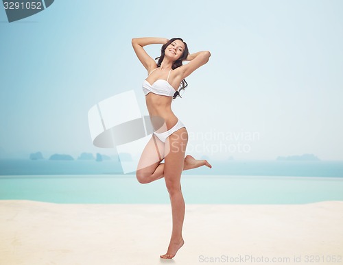 Image of happy young woman in white bikini swimsuit