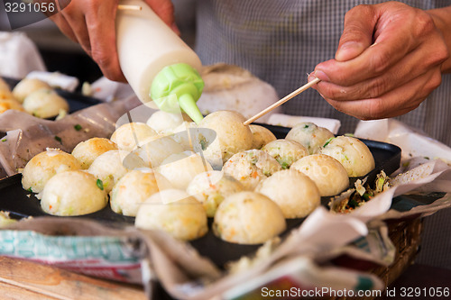 Image of cook stuffing dough or rice balls at street market