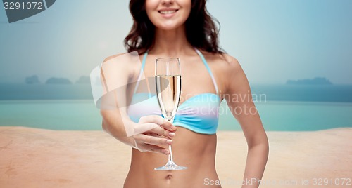 Image of happy young woman in swimsuit drinking champagne