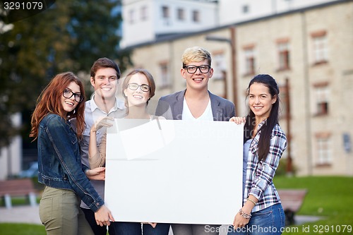 Image of happy teenage students holding white blank board