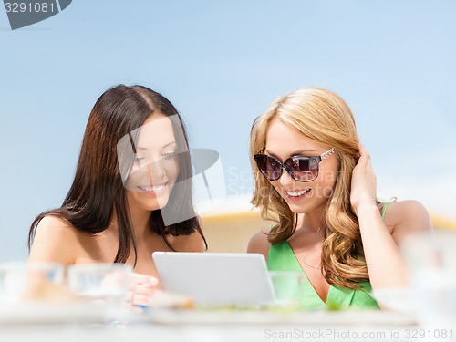 Image of smiling girls looking at tablet pc in cafe