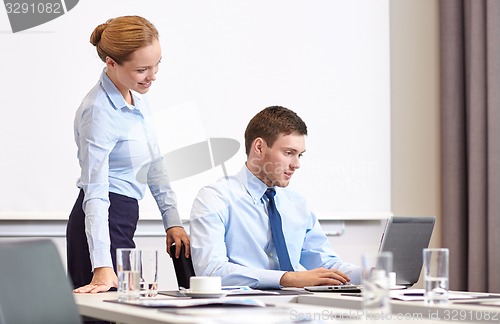 Image of businessman and secretary with laptop in office