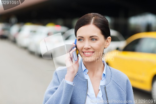 Image of smiling woman with smartphone over taxi in city