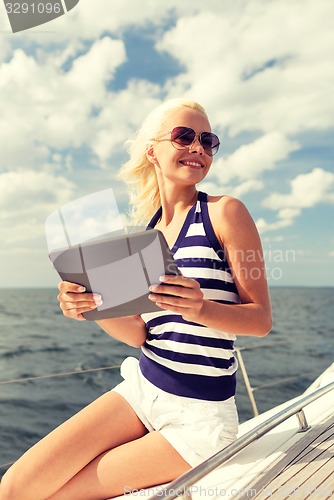 Image of smiling woman sitting on yacht with tablet pc