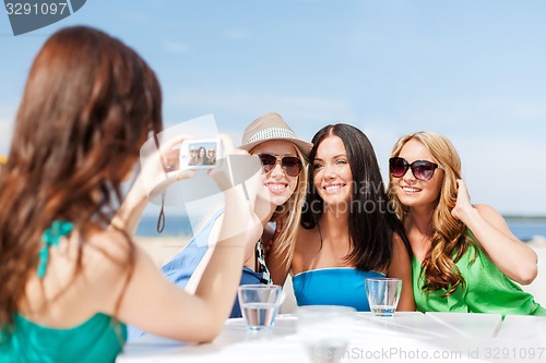 Image of girls taking photo in cafe on the beach