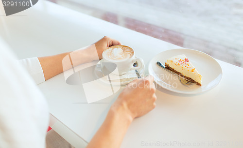 Image of close up of woman hands with cake and coffee