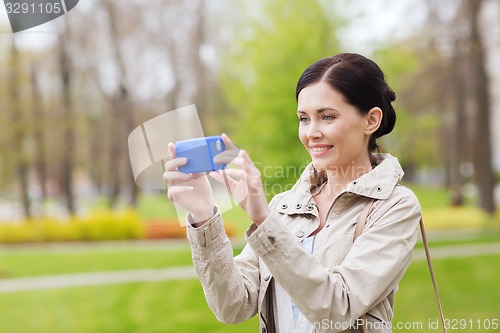 Image of smiling woman taking picture with smartphone