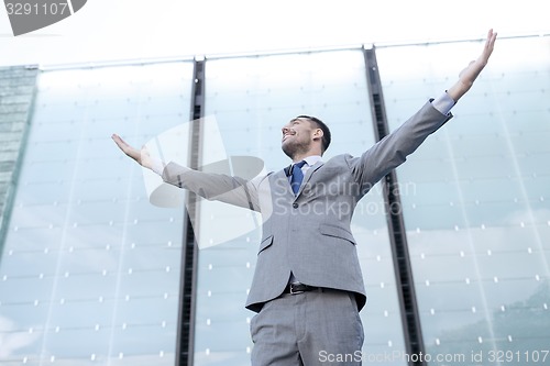 Image of young smiling businessman over office building