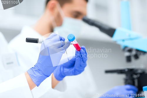 Image of close up of scientists hands with test tube in lab