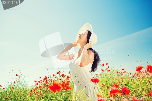 Image of smiling young woman in straw hat on poppy field