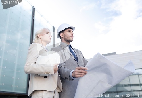 Image of businessmen with blueprint and helmets