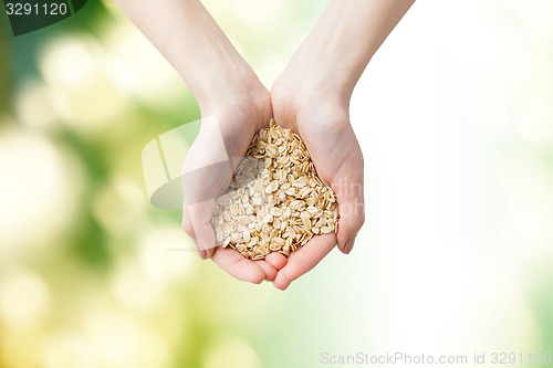 Image of close up of woman hands holding oatmeal flakes