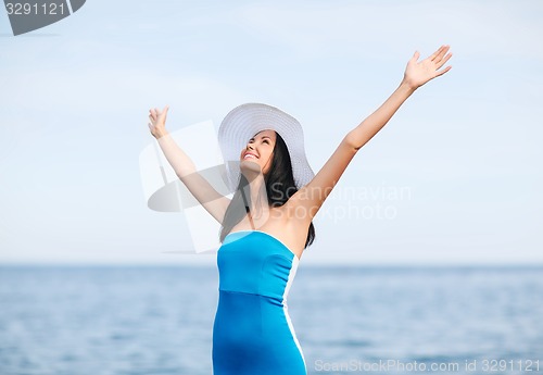 Image of girl with hands up on the beach