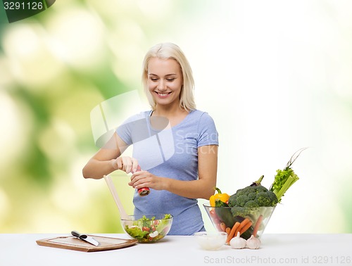 Image of smiling woman cooking vegetable salad