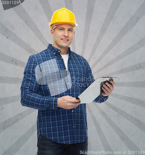 Image of smiling male builder in helmet with clipboard