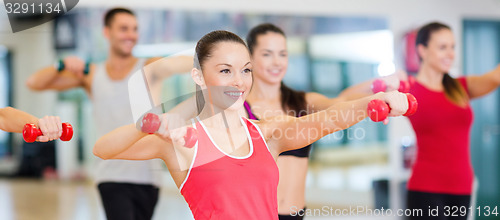 Image of group of smiling people working out with dumbbells
