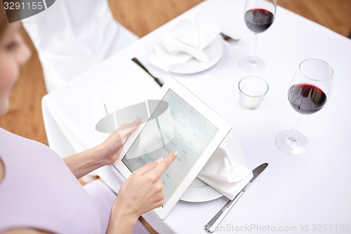 Image of close up of woman with tablet pc at restaurant