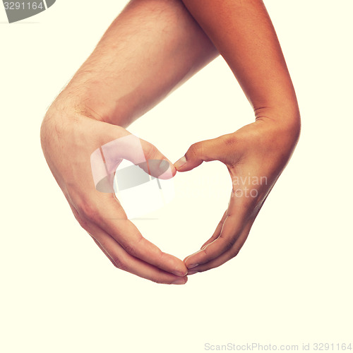 Image of woman and man hands showing heart shape