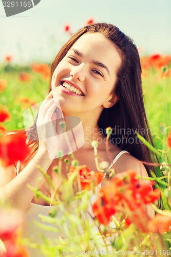 Image of smiling young woman on poppy field