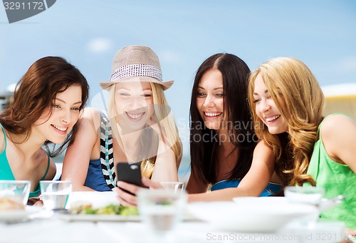 Image of girls looking at smartphone in cafe on the beach