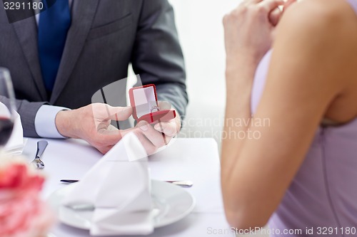 Image of excited young woman and boyfriend giving her ring