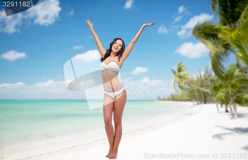 Image of happy woman in bikini swimsuit dancing on beach